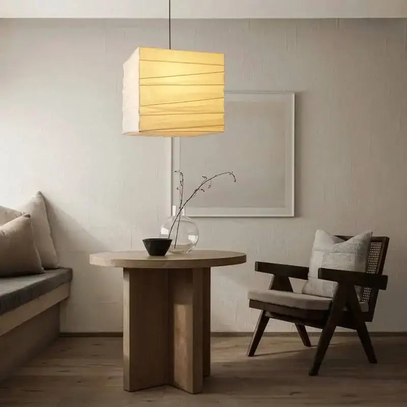 Beige and white cube rice paper pendant lamp with warm-toned horizontal slats hanging above wooden table decorbites cube rice