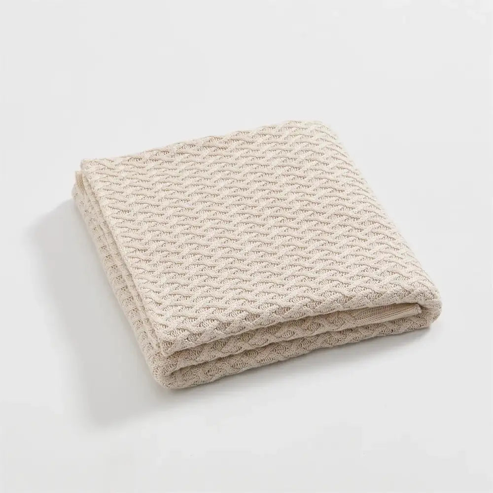 A neatly folded beige knitted bamboo throw blanket with a waffle pattern for decorbites cool summer air conditioning