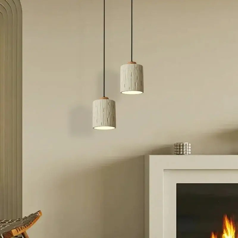 Two beige wood grain columnar micro cement pendant lights with textured ceramic finish and dark metal cords for decorbites decor
