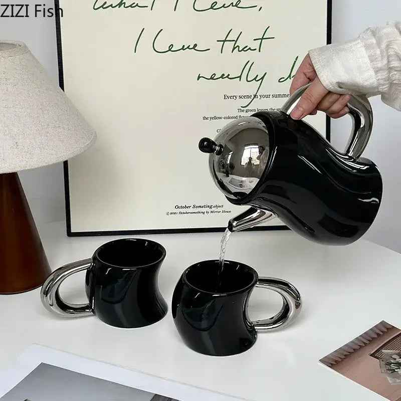 Black ceramic bending design teapot with silver lid and handle pouring into matching mugs from decorbites design ceramic coffee set