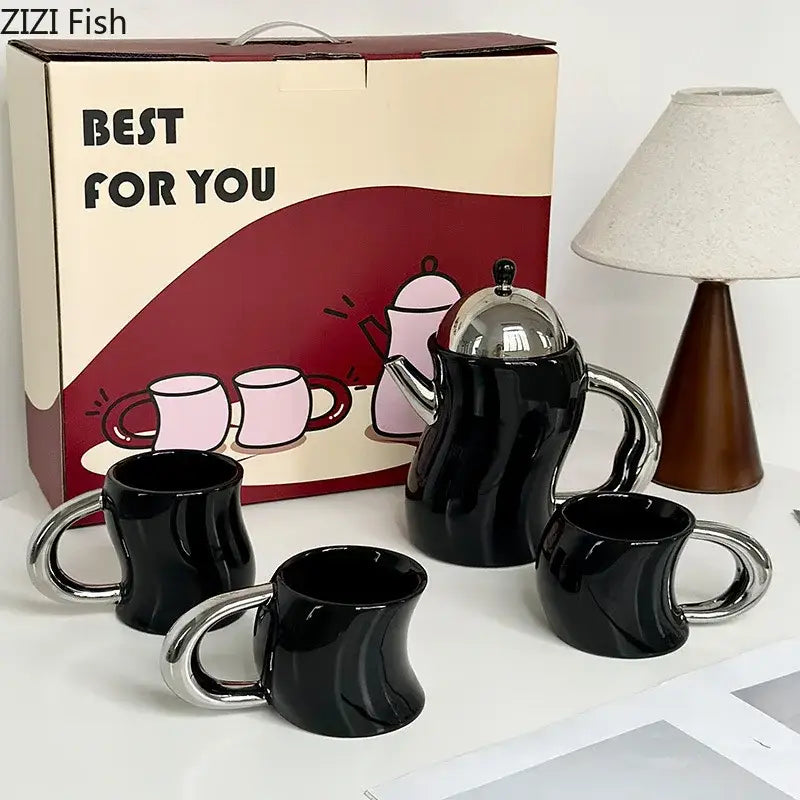 Black ceramic teapot with shiny silver lid and handle and three matching bending design ceramic coffee mugs with chrome handles