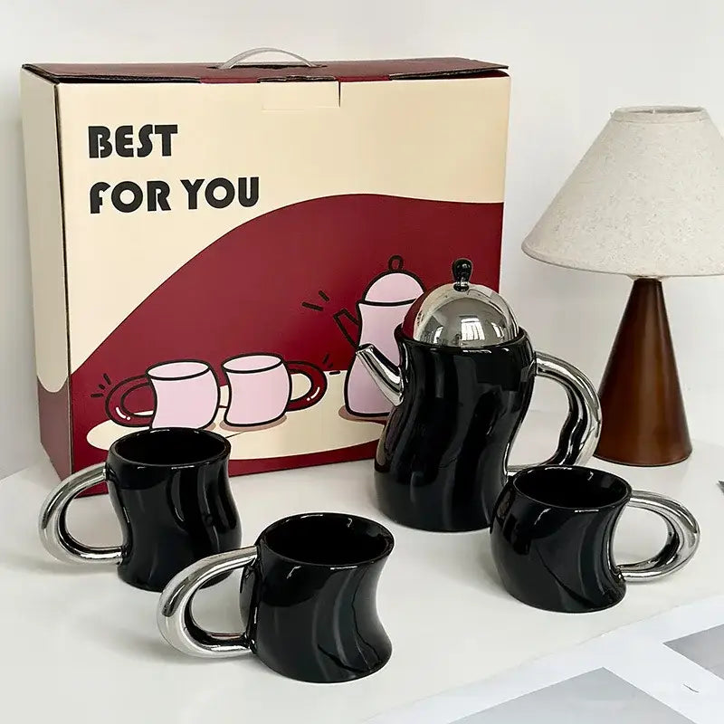 Black ceramic teapot with shiny silver lid and handle and three matching bending design ceramic coffee mugs with chrome handles