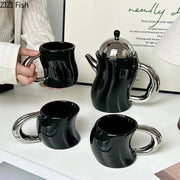 Set of three black bending design ceramic mugs with chrome handles and matching teapot with silver lid for decorbites dining