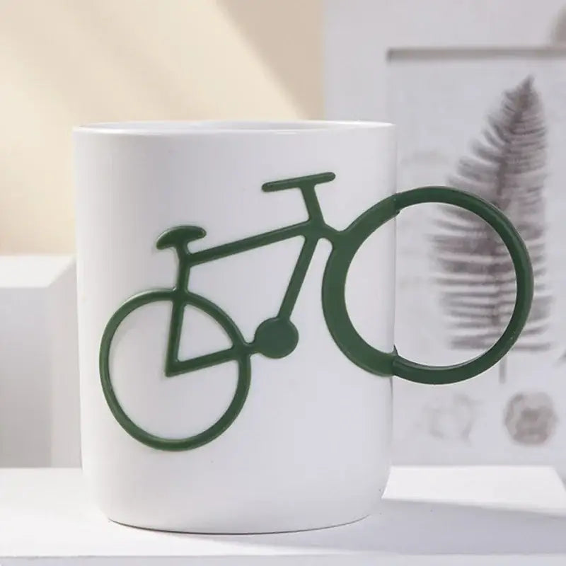 White ceramic toothbrush holder cup featuring a dark green bicycle design forming the handle for bathroom use
