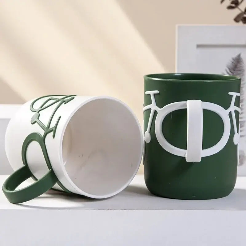 Green ceramic toothbrush holder cup with white bicycle design and handle for bathroom use