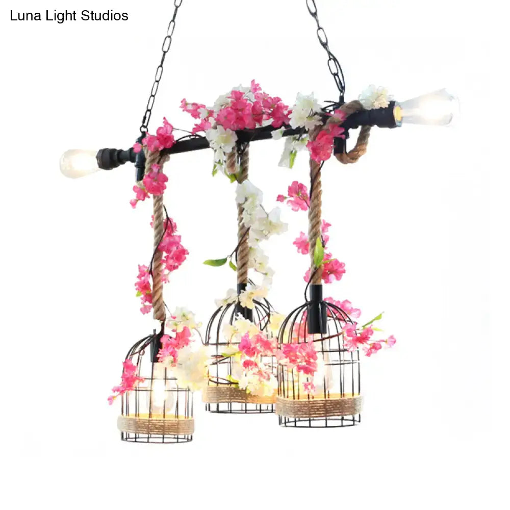 A rustic rose red metal birdcage chandelier with three hanging lights wrapped in natural twine and adorned with artificial flowers