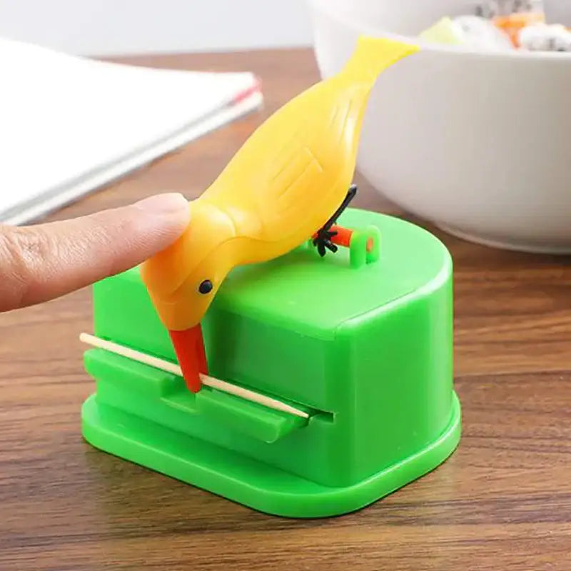 Yellow plastic birdie toothpick holder with orange beak and black feet mounted on a green base decorbites toothpick holder