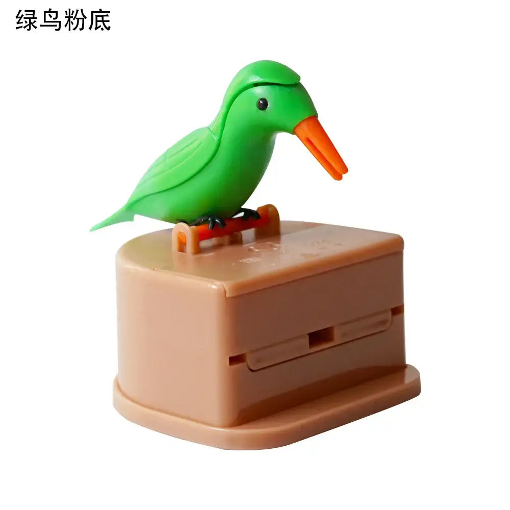 Green bird-shaped automatic toothpaste dispenser with orange beak and black feet on beige base for birdie toothpick holder