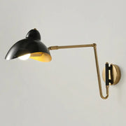 Black and brass adjustable joint wall lamp with sleek curved arm designed as a duckbill reading light for bedrooms