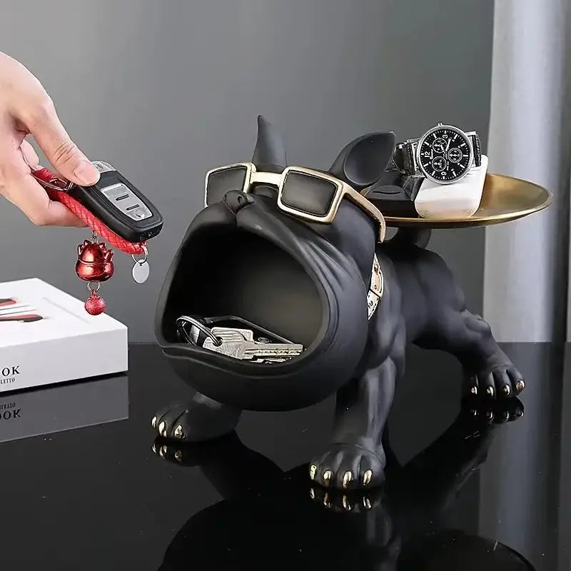 Black and gold french bulldog figurine with metallic claws and sunglasses serving as remote control storage tray