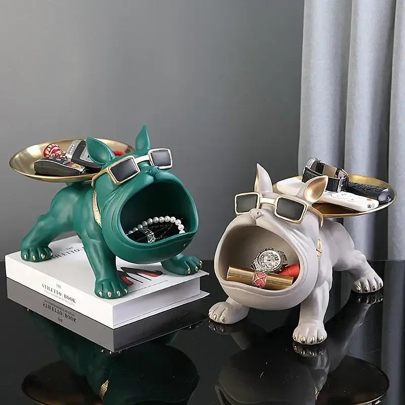 Green and white resin french bulldog figurines with gold sunglasses holding jewelry in black and gold remote control storage tray