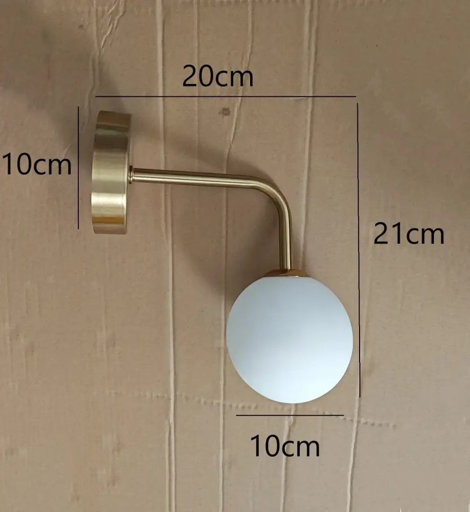 A sleek brass-finished wall lamp with frosted white spherical glass shade for decorbites golden glass led lighting