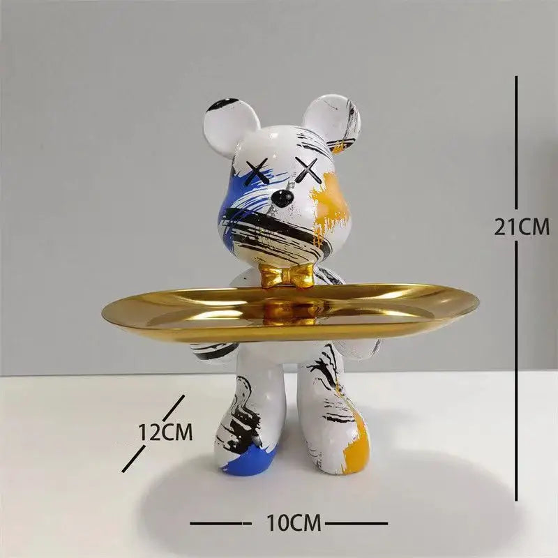 White bear figurine with blue black and yellow paint splatters and x shaped eyes holding a gold tray decorbites graffiti bear
