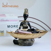 Black and gold resin black woman figurine holding a leaf-shaped tray ideal for living room decorbites black woman decor
