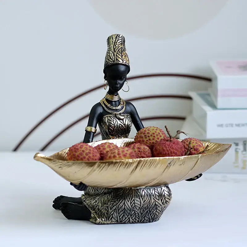 Black and gold resin black woman figurine holding leaf-shaped bowl filled with lychees for living room decorbites tray