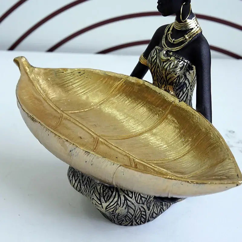 Black woman resin figurine in black and gold holding a large golden leaf tray for living room decorbites decor