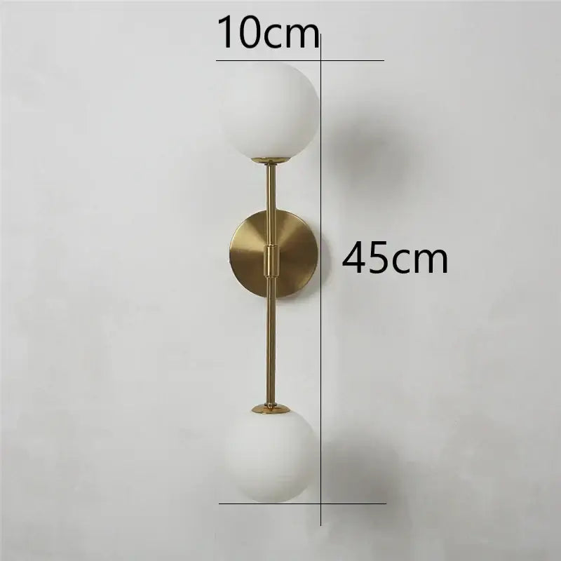 A modern wall lamp with brushed gold finish and two frosted glass shades decorbites golden glass led bedroom sconce