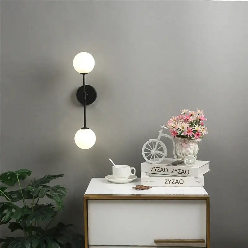 Modern black wall lamp with two spherical white glass globes featuring decorbites golden glass led accents for bedroom use