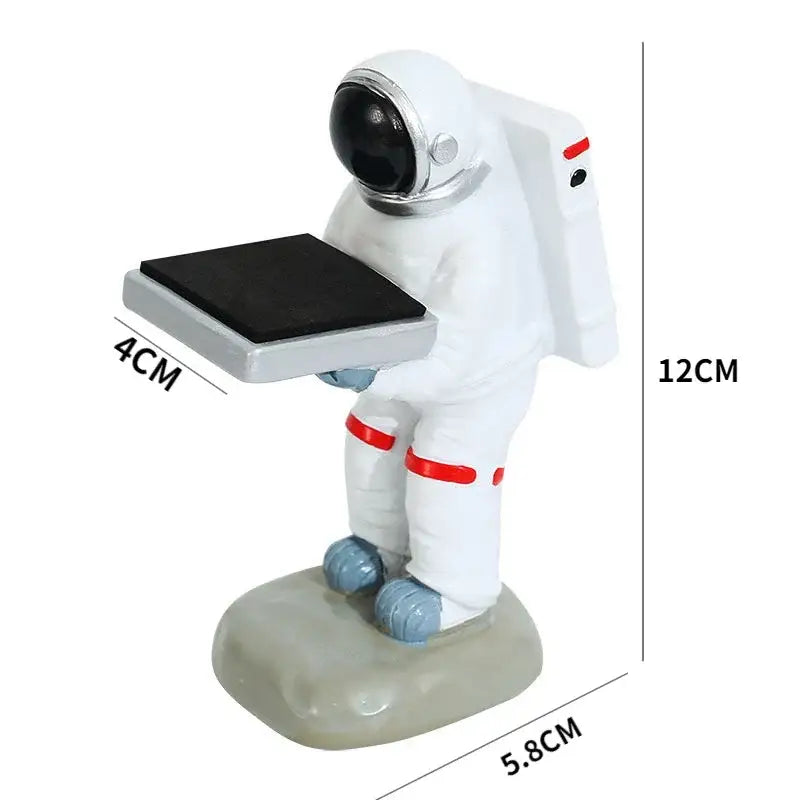 White astronaut figurine with red accents and silver helmet holding black solar panel on cartoon bear watch stand