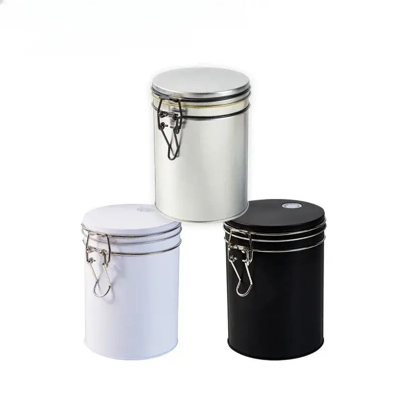 Three cylindrical metal food storage pots in white black and silver with hinged lids for hermetic food storage by decorbites