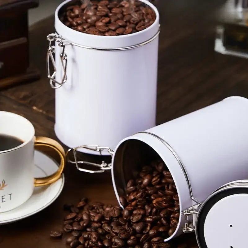 Decorbites hermetic food storage white cylindrical metal canister with silver clasp filled with roasted coffee beans