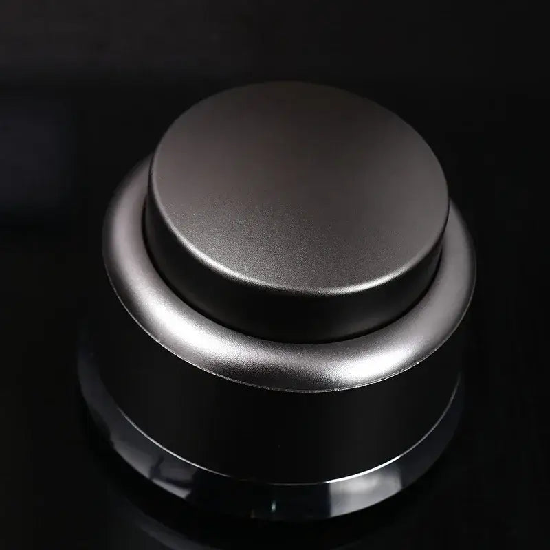 A sleek black and stainless steel decorbites adjustable coffee tamper with matte finish circular top and cylindrical base