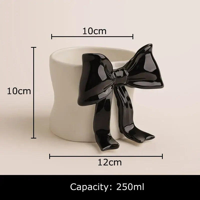 A white porcelain coffee cup with rounded edges and a glossy black bowknot accent for dining room use