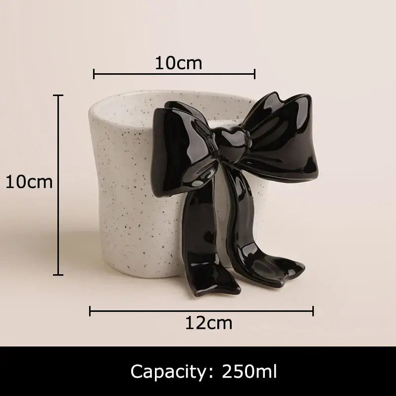 A porcelain coffee cup featuring a speckled white ceramic body with a sleek black glossy bowknot accent on the side