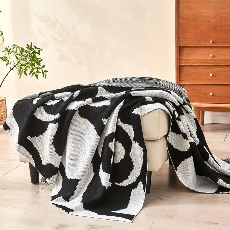 Black and white camellia knitted blanket with bold rose pattern draped over armchair for living room decorbites camellia