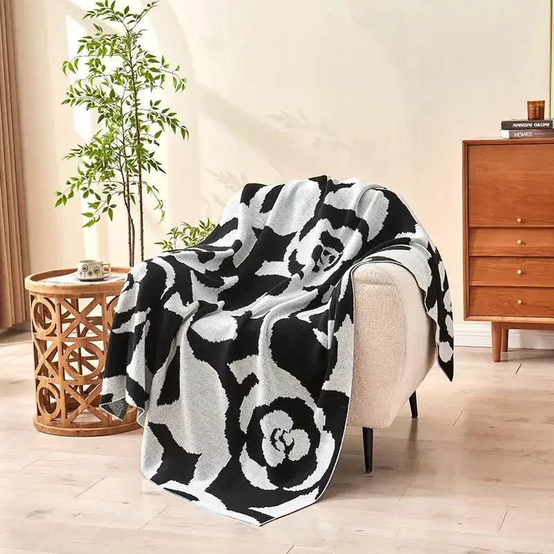 Black and white camellia knitted blanket draped over chair showing decorbites camellia knitted floral throw quilt
