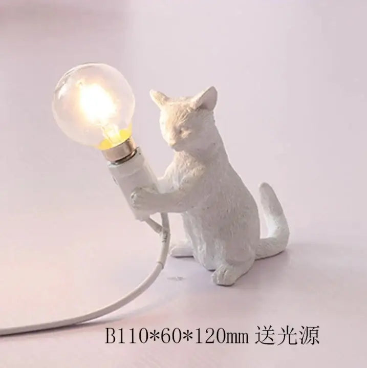 White ceramic cat resin table lamp holding a glowing bulb for bedroom decor by decorbites cat resin
