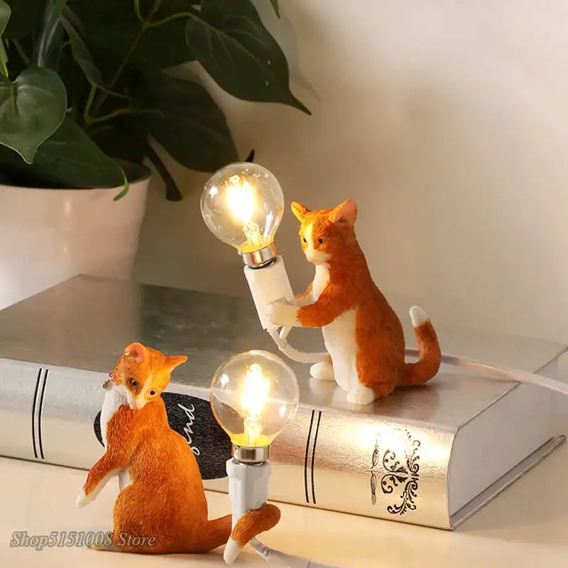 Orange and white resin cat figurines holding illuminated edison bulbs in a decorbites cat resin table lamp for bedroom decor