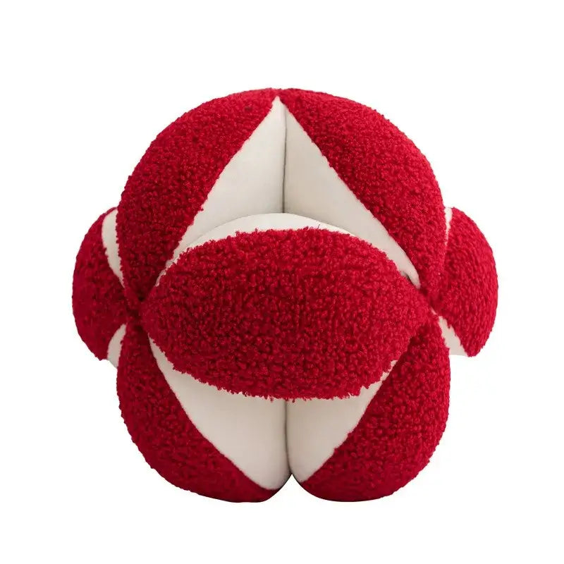 A plush red and white textured spherical toy paired with a black and white jungle plant raccoon pillow cover decorbites decor