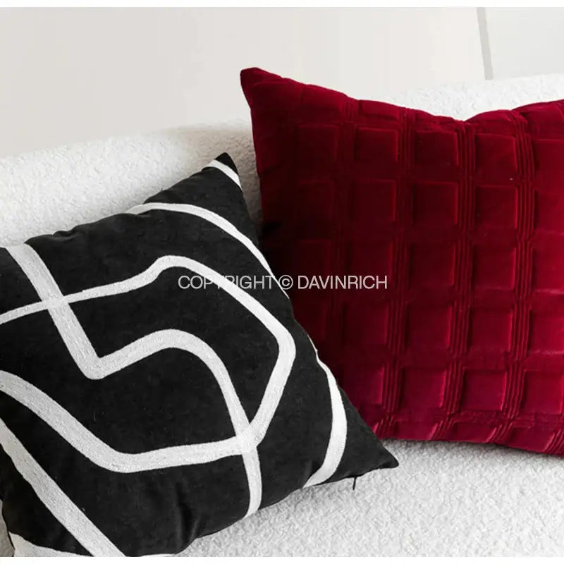 A plush black pillow cover with bold white abstract stitching on a red velvet quilted cushion for decorbites jungle plant raccoon decor