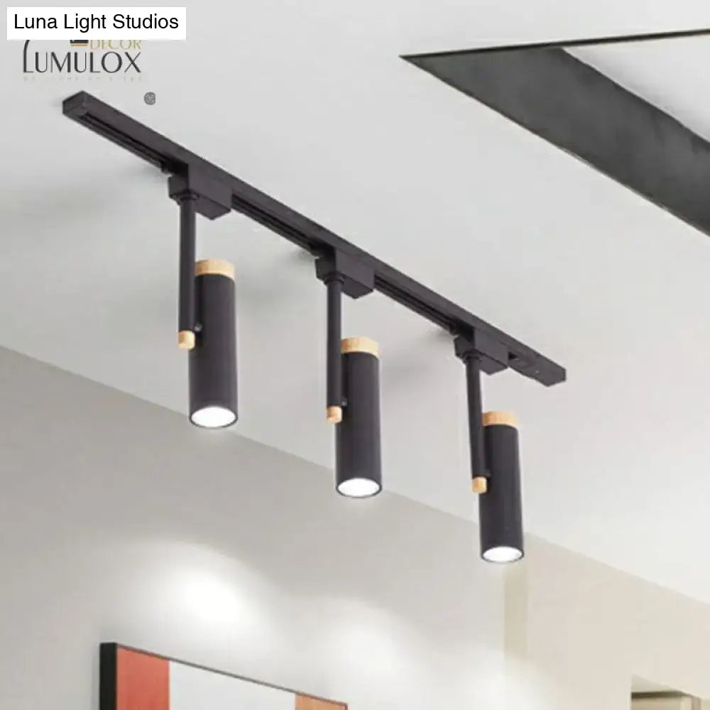 Black cylindrical DecorBites Nordic tubular metallic spotlight with wood cap mounted on a sleek metal rail