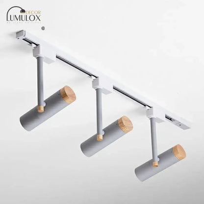 Modern gray cylindrical track lights with natural wood caps mounted on sleek white rail by decorbites™