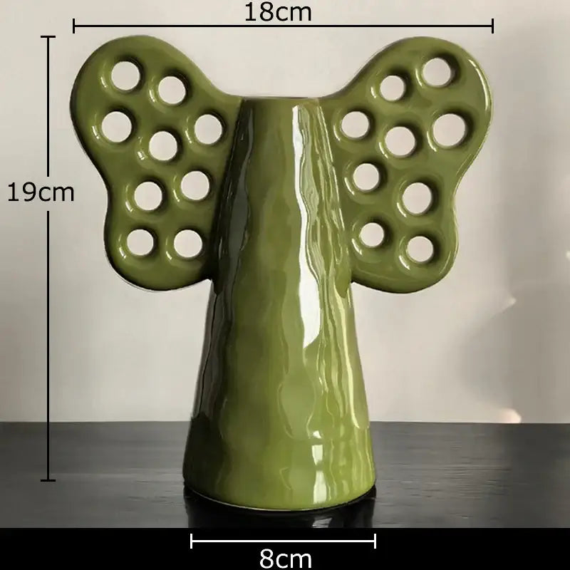 Glossy olive-green decorbites elephant ceramic vase shaped like an angel with butterfly wings holding artificial flowers