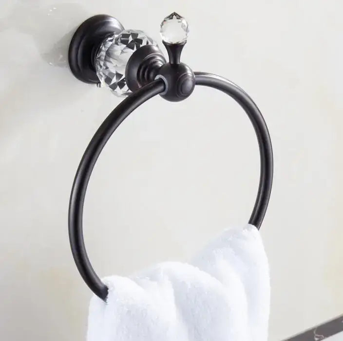 Black brass bathroom accessories set featuring a black metal towel ring with crystal accents holding a white towel