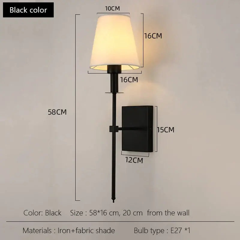 Black brass wall sconce with black iron frame and cream fabric shade for bedroom lighting