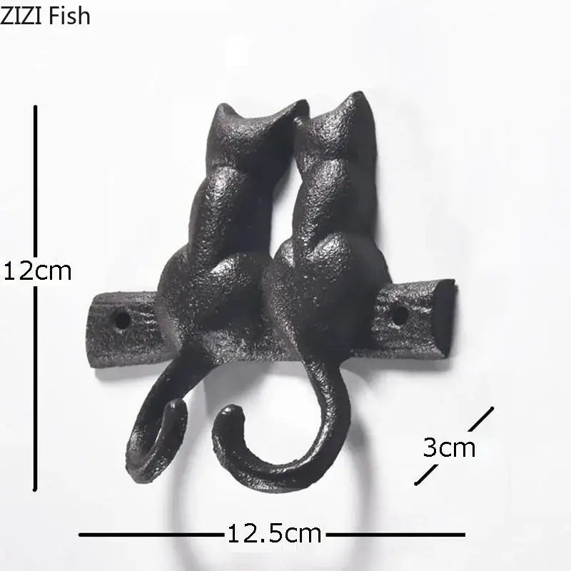 Black cast iron cat hook shaped like two cats with curved tails forming hooks for hanging shelf outdoor decorbites decor