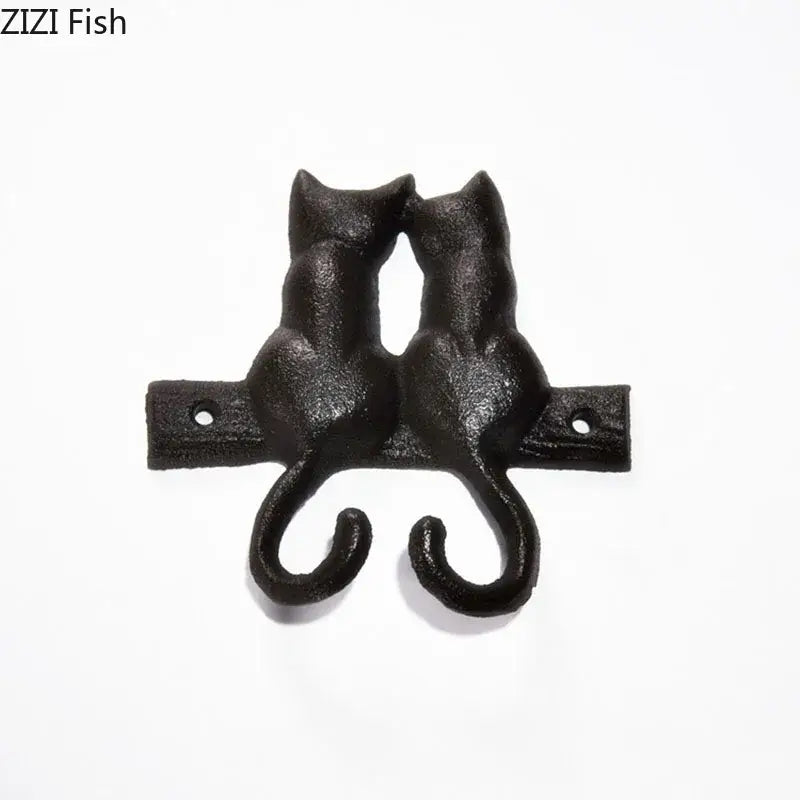 Black cast iron cat hook shaped like two cats back-to-back with curved tails for hanging shelf outdoor wall decor