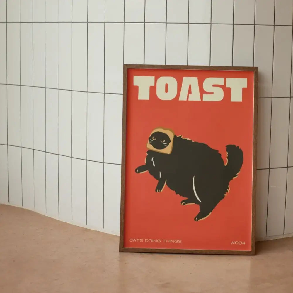 A framed DecorBites™ wall art canvas with a bold red background featuring a funny black cat wearing toast as a hat