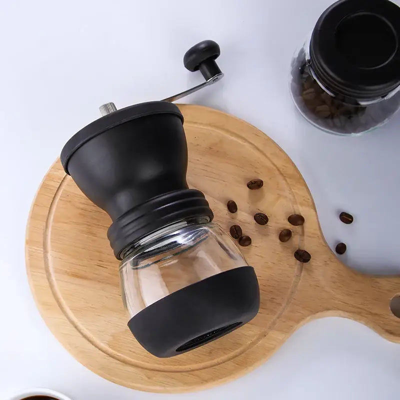 Black ceramic hand rocking coffee grinder with glass container and rubberized grip for manual kitchen milling