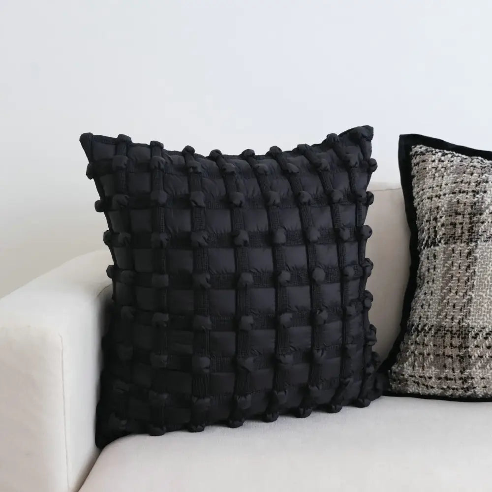 Black dot bubble quilted cushion cover with textured woven pattern and pom pom accents for home decor