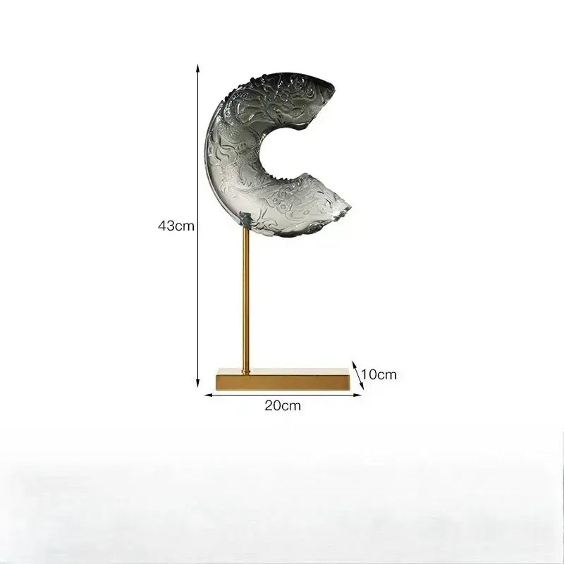 A translucent gray black glass dragon sculpture with intricate carvings on a gold-toned stand decorbites crescent moon decor