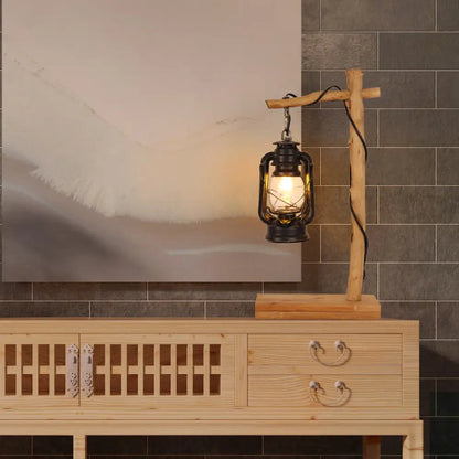 Lámpara de mesa de noche de cristal negro con soporte en cruz de madera.