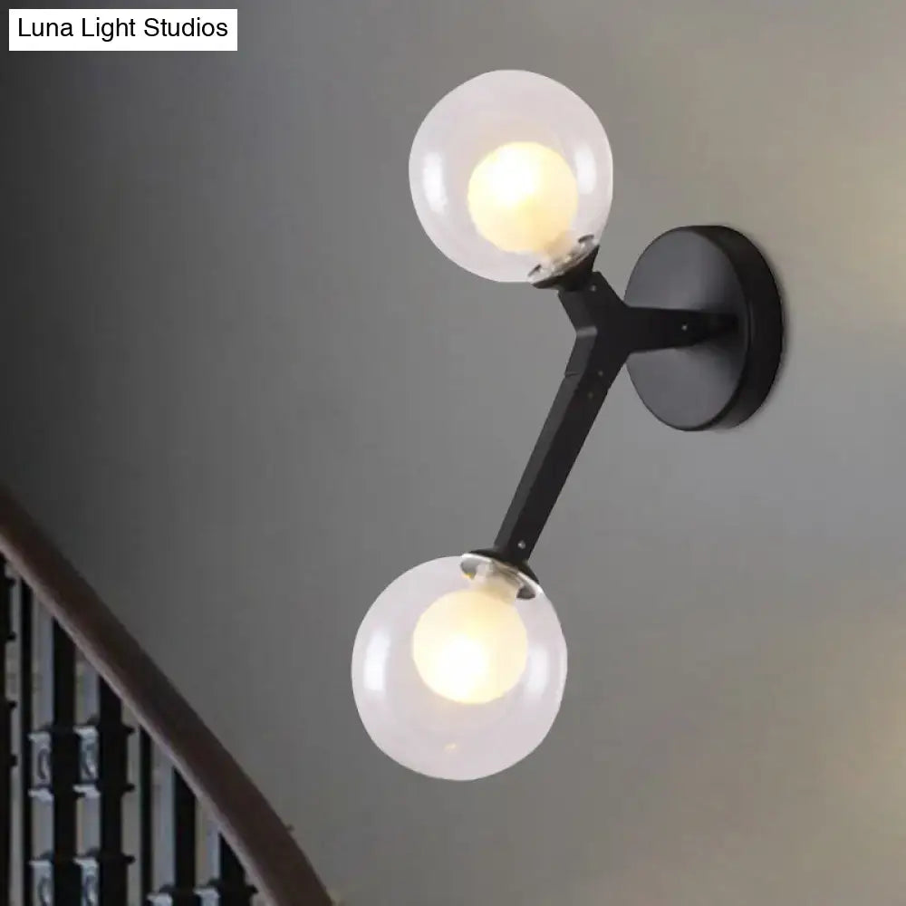 Black metal wall sconce with two frosted glass globe shades in a black and gold bubble wall sconce design