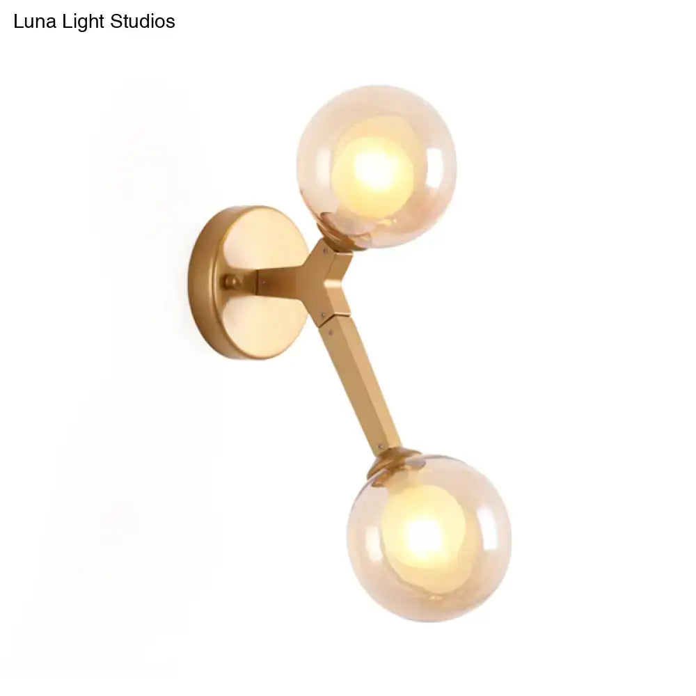 Black and gold bubble wall sconce with two amber glass globes designed as a stylish bedroom glass globe light