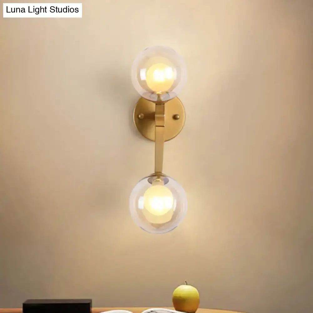 Gold-toned black and gold bubble wall sconce with two clear glass globe shades for bedroom lighting