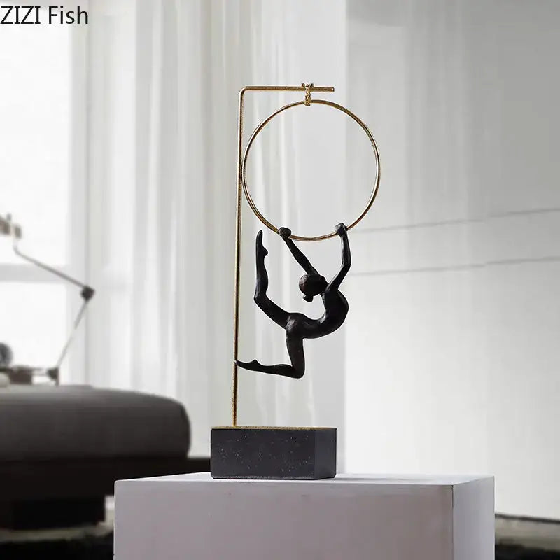 Black matte gymnastic acrobat resin sculpture hanging from gold hoop on dark stone base by decorbites for living room decor